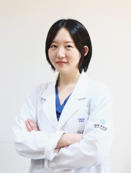 Dr. Kim Joo-hee of Grand Plastic Surgery, portrait in a white coat with arms folded